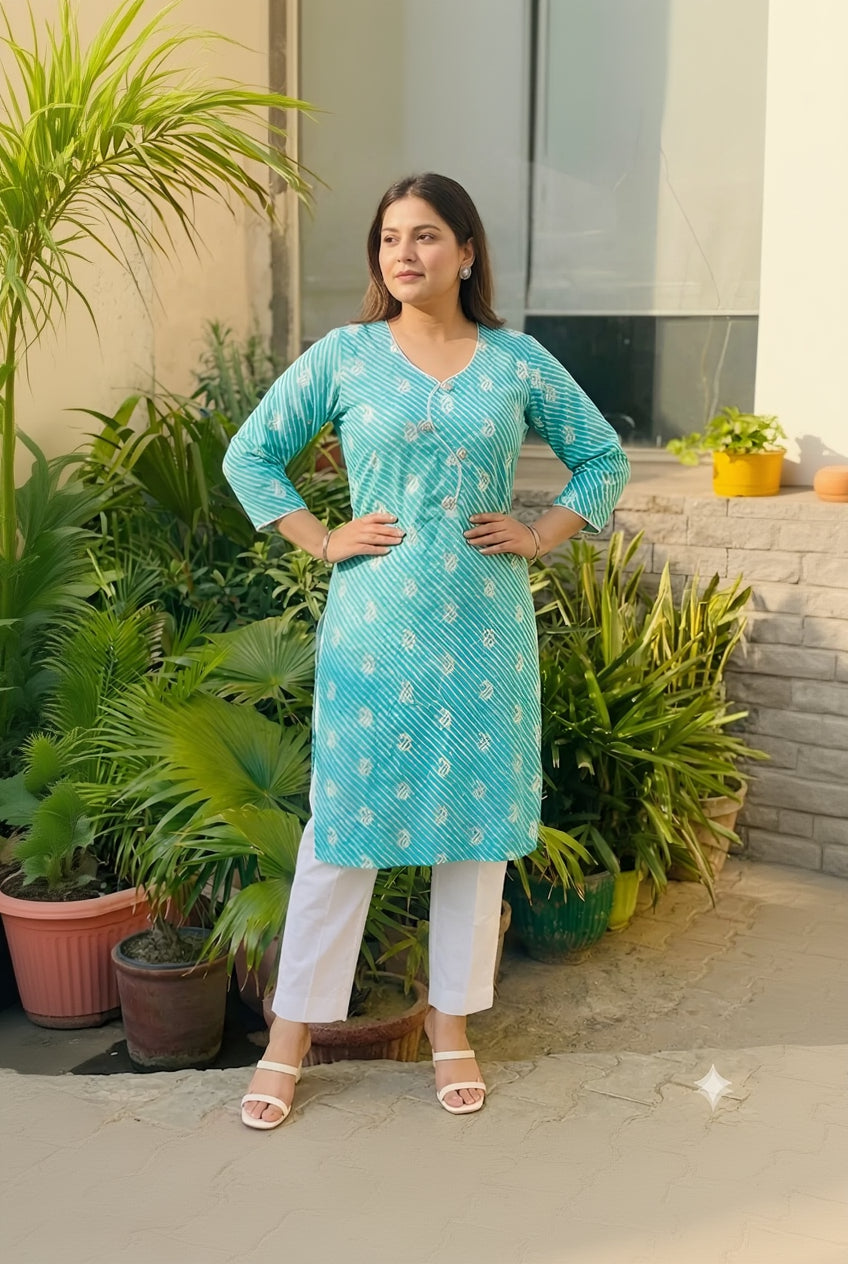 Woman wearing a turquoise patterned kurta with white pants standing outdoors.
