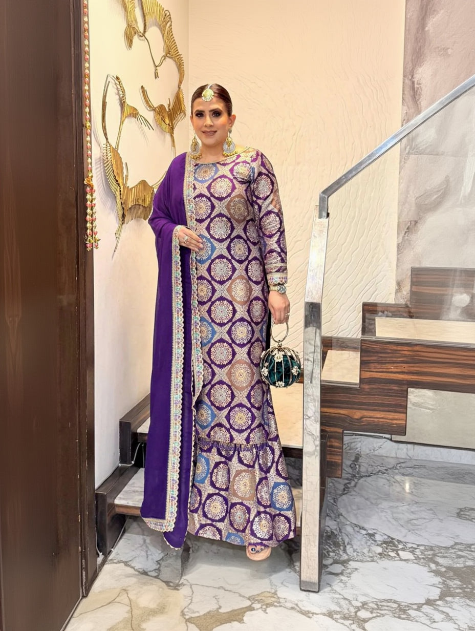 A woman wearing a traditional purple Banarasi silk suit with gold and silver patterns, paired with a dupatta and golden accessories.