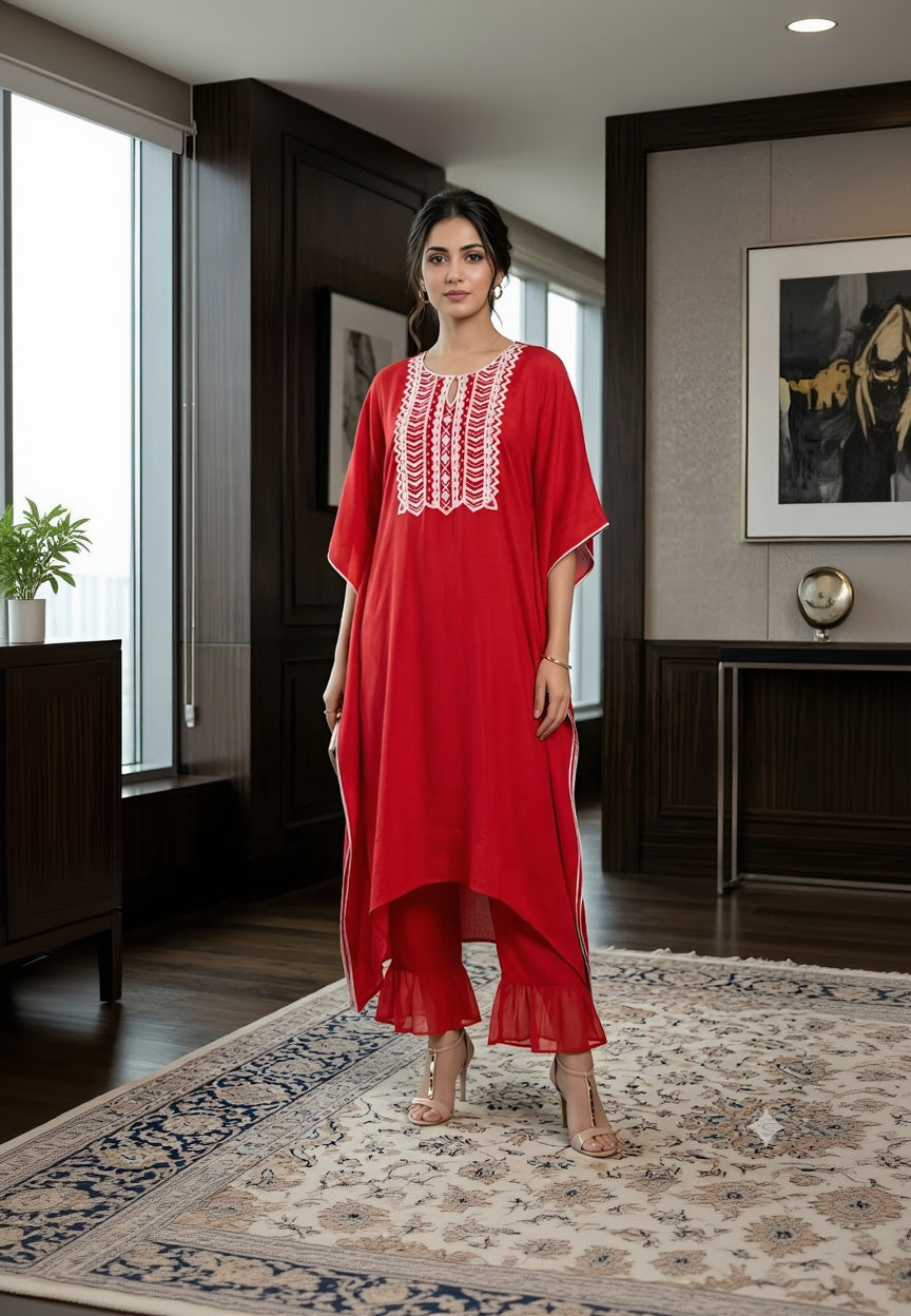 Woman wearing a red dress with white embroidery in a room.