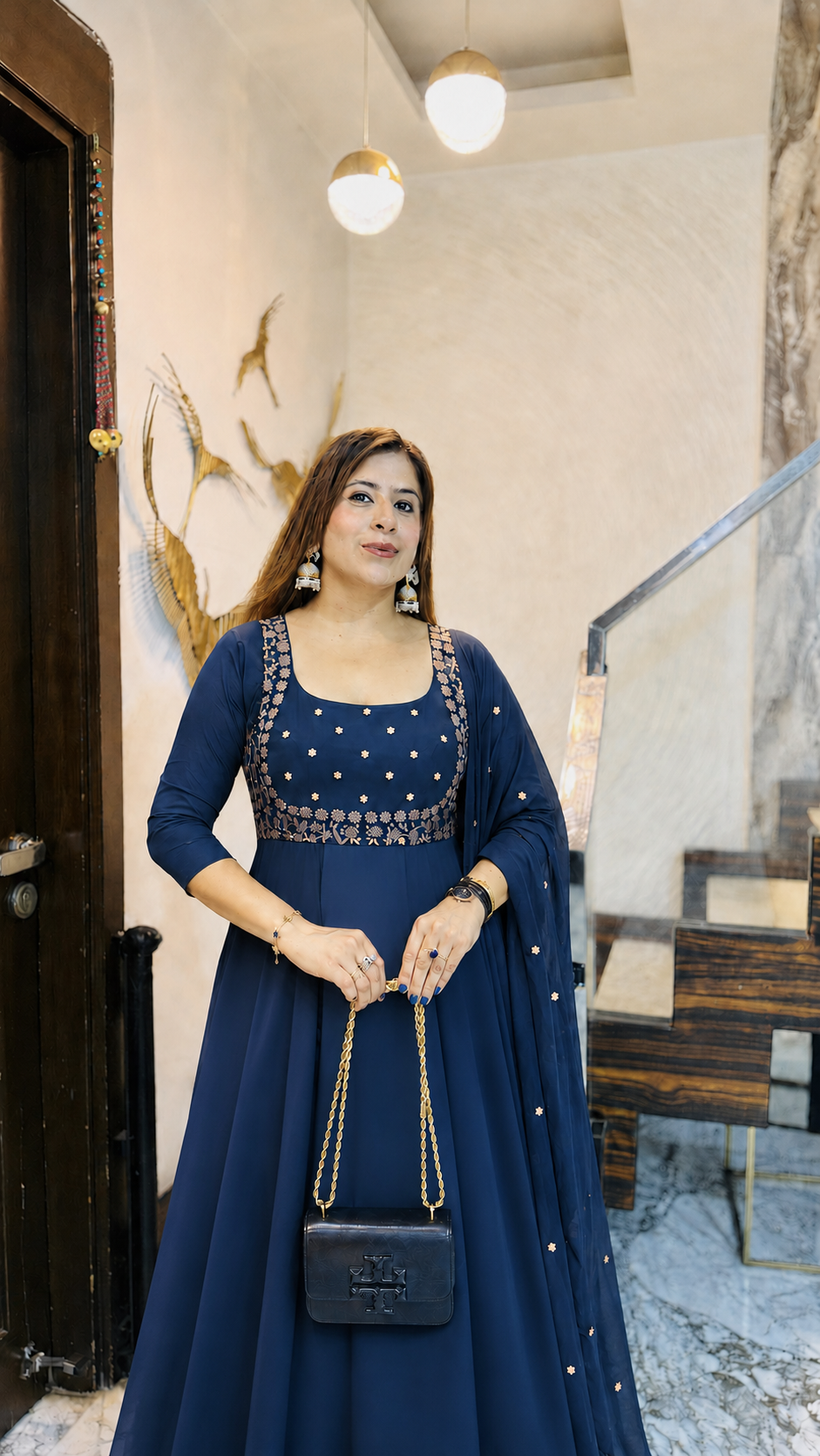 Woman in a blue dress standing in a room with decorative elements.