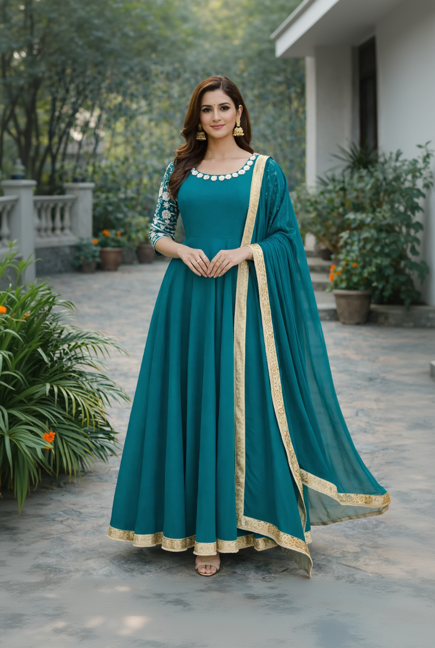 Woman wearing a teal dress with gold trim outdoors.