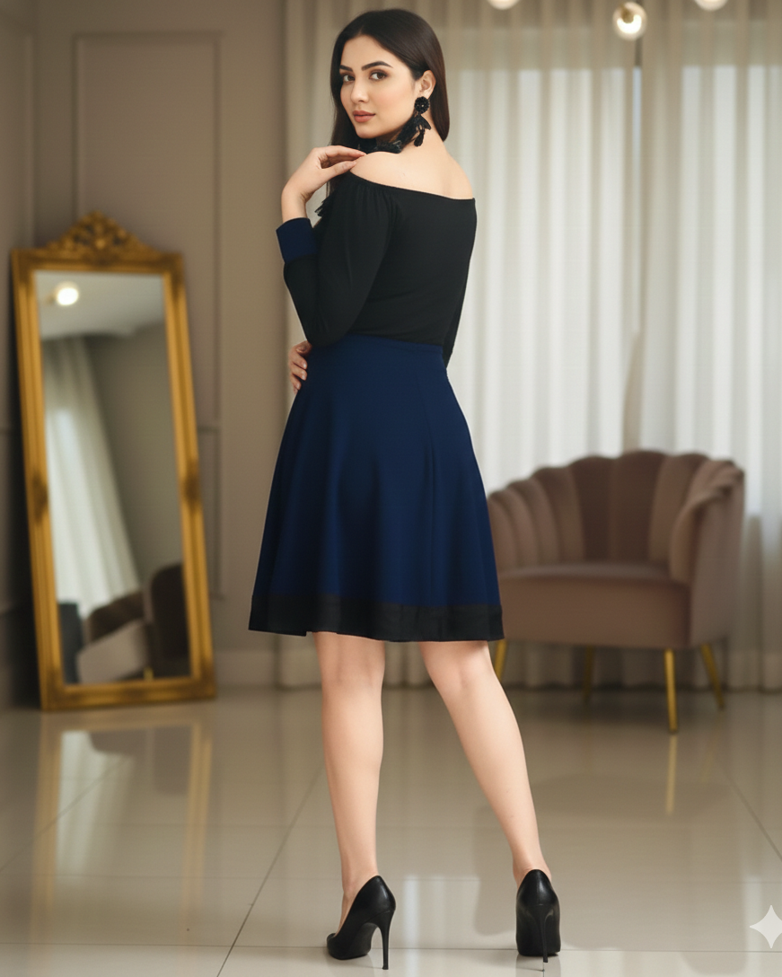 Woman wearing a black and navy dress standing in a room with a mirror and chair.