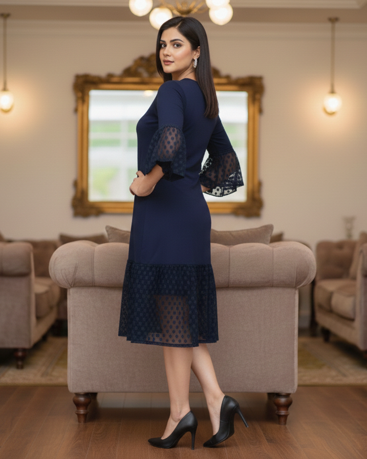 Woman in a navy blue dress standing in a living room.