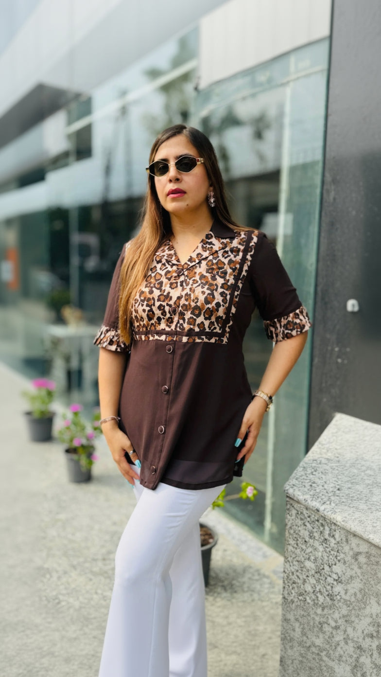 Woman wearing a leopard print top and white pants standing outdoors.