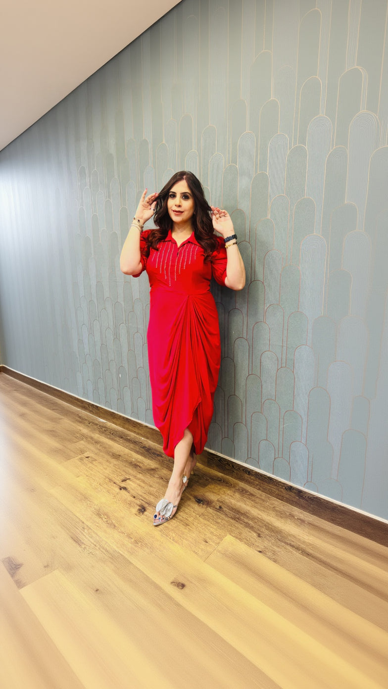 Woman in a red dress posing against a patterned wall.