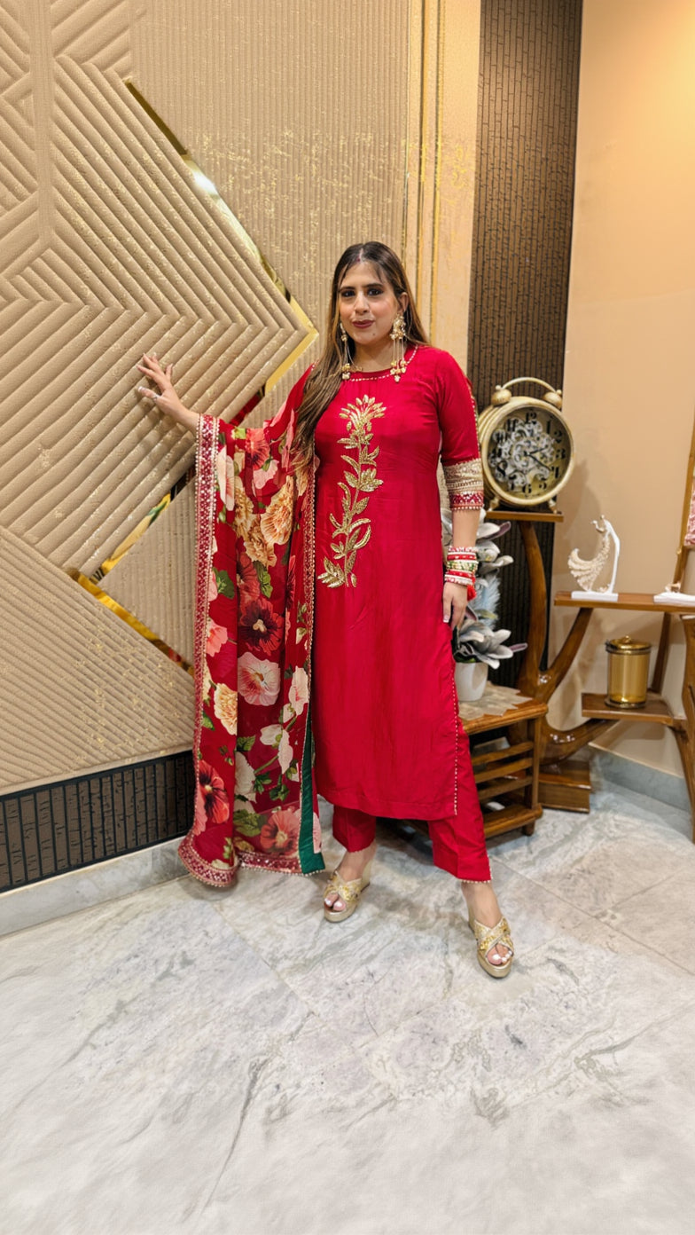 Woman in a red traditional outfit with floral patterns indoors.