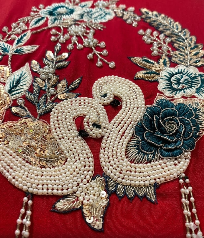 Decorative patch with embroidered swan and floral elements on a red background