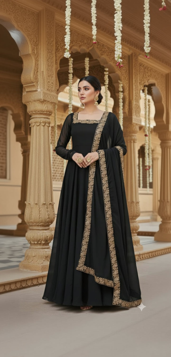 Woman in a black traditional outfit with gold embroidery standing in an ornate architectural setting.