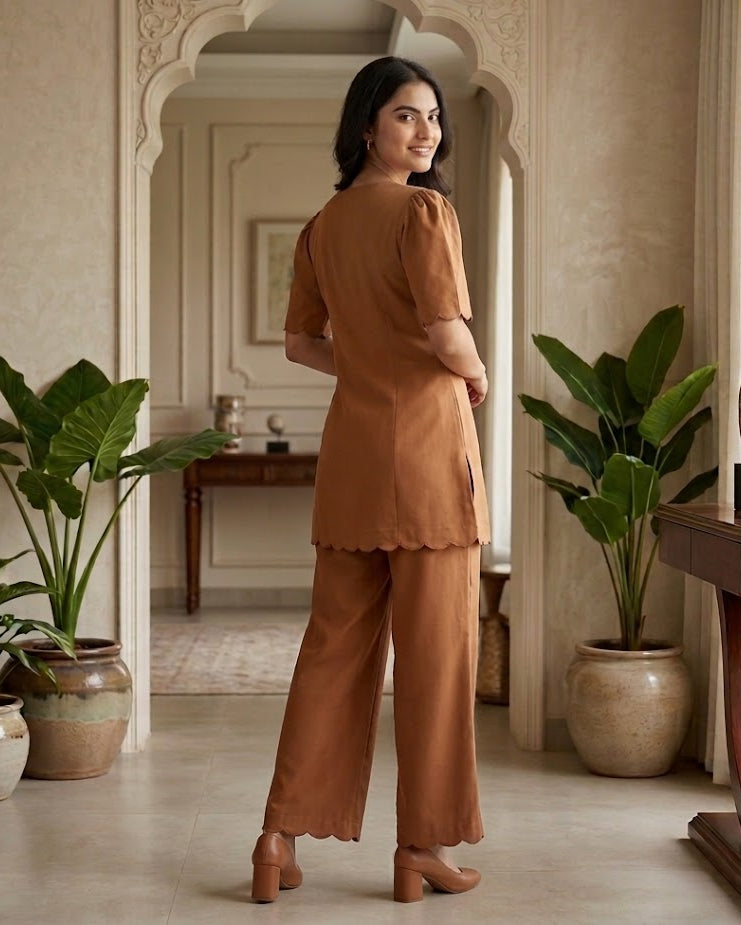 Woman in a brown outfit standing in a room with plants and decor.