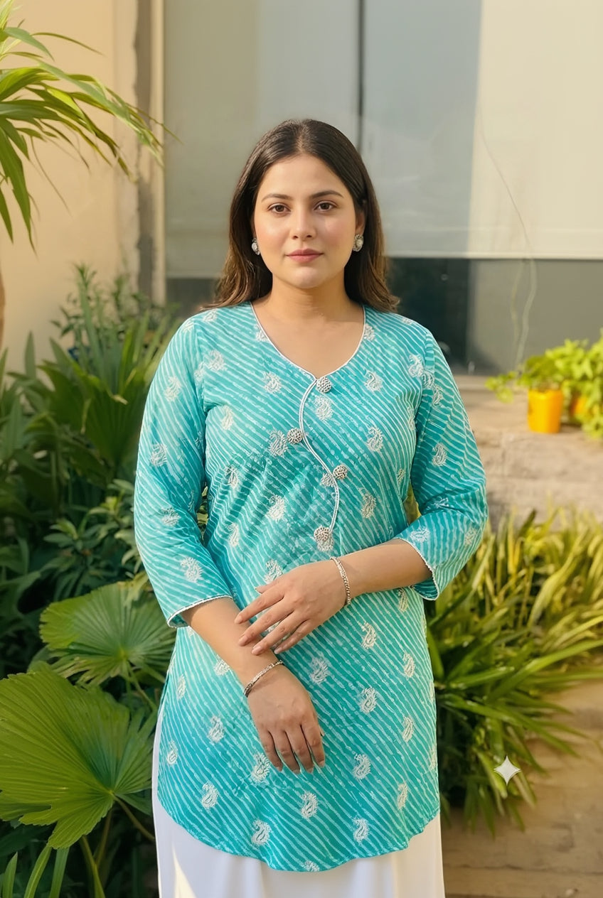 Woman wearing a turquoise patterned kurta with white pants standing outdoors.