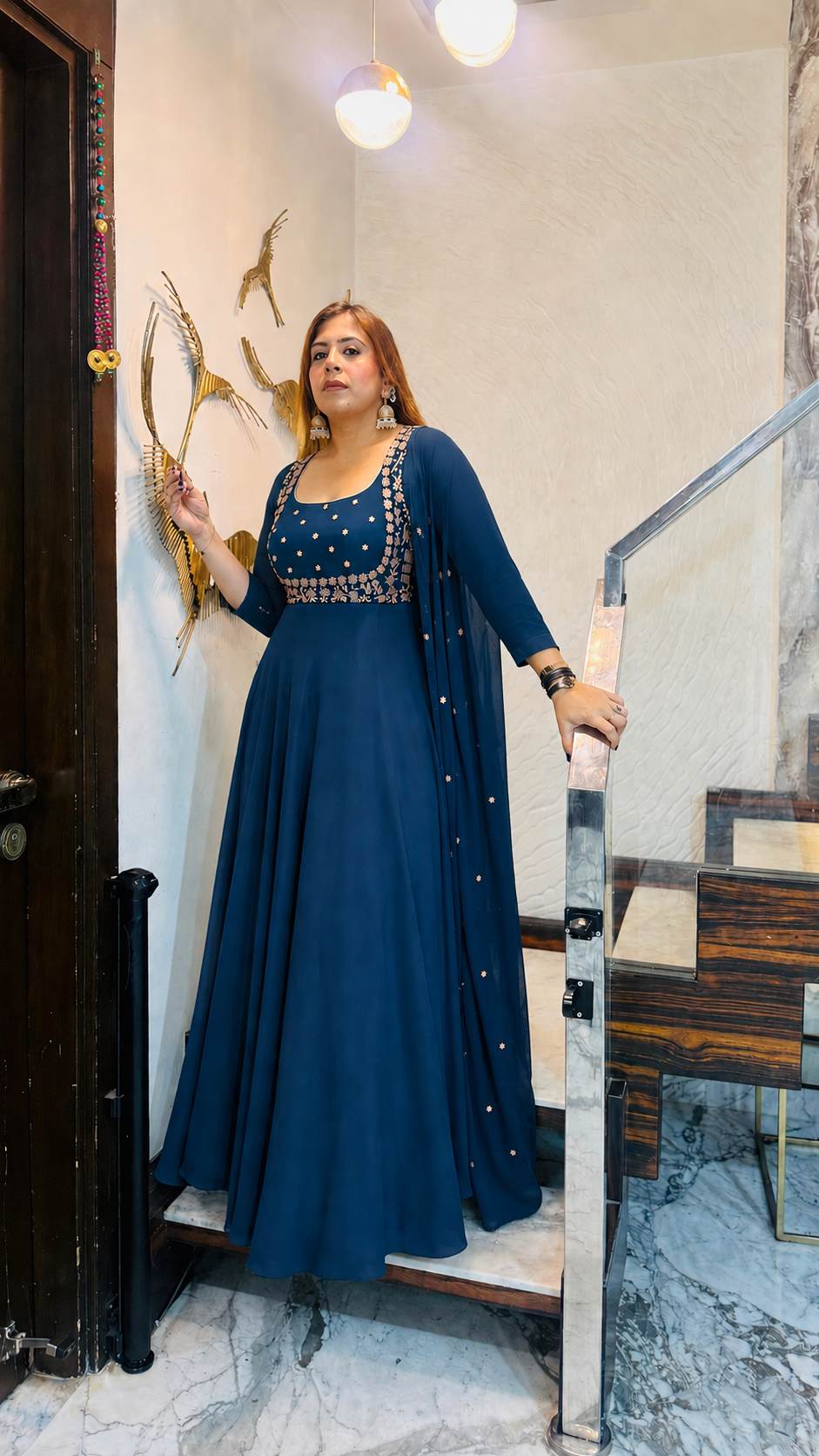Woman in a blue dress standing in a room with decorative elements.