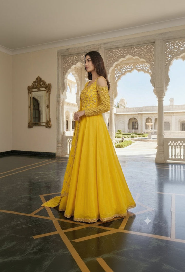 Woman in a yellow dress standing in an ornate indoor setting with a garden view.