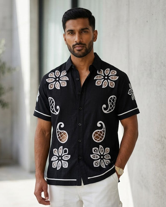 Man wearing a black floral patterned shirt in an indoor setting