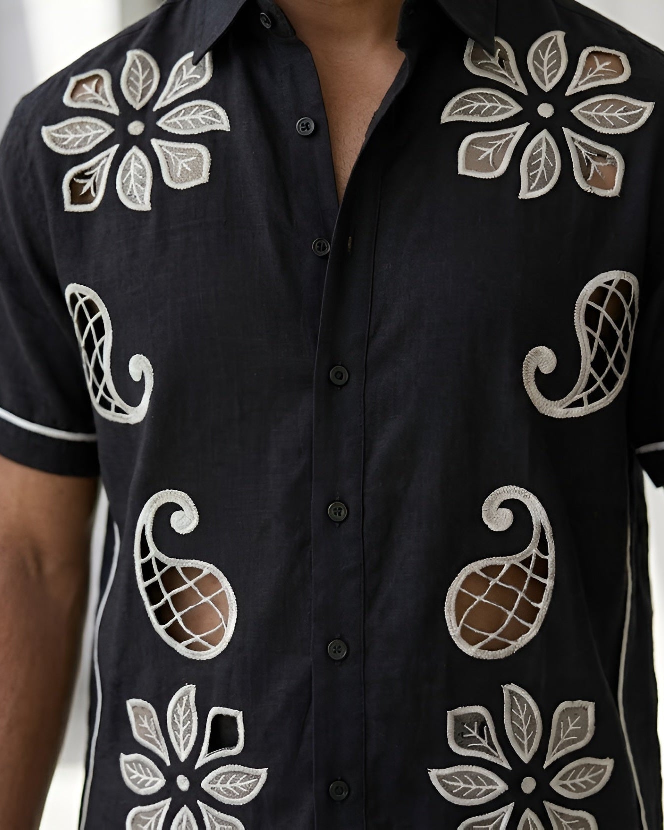 Black shirt with white floral patterns worn by a person indoors