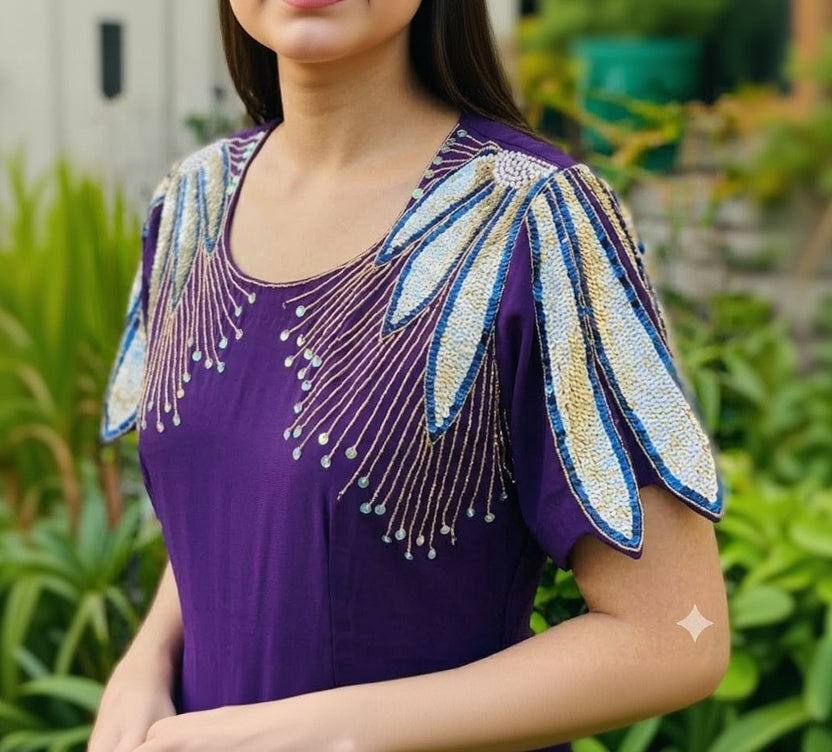 Purple top with floral embellishments and beads against a blurred green background